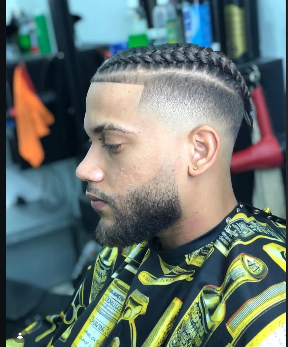 Trenzas con degradado limpio y barba definida